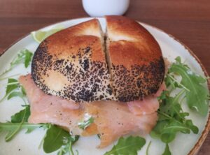 EN A homemade bagel filled with smoked salmon, smooth cream cheese and fresh rocket, served at Artist Cafe in Shoreditch near Old Street. CN 自制贝果，夹有烟熏三文鱼、奶油奶酪和芝麻菜，于 Shoreditch 的 Artist Cafe 提供。 ES Bagel casero con salmón ahumado, queso crema y rúcula, servido en Artist Cafe Shoreditch. FR Bagel maison garni de saumon fumé, fromage frais et roquette, servi à l’Artist Cafe Shoreditch. DE Hausgemachter Bagel mit Räucherlachs, cremigem Frischkäse und Rucola, serviert im Artist Cafe Shoreditch. IT Bagel fatto in casa con salmone affumicato, formaggio cremoso e rucola, servito all’Artist Cafe Shoreditch. JA 自家製ベーグルにスモークサーモン、クリームチーズ、ルッコラを挟んだ一品。Shoreditch の Artist Cafe にて提供。 NL Huisgemaakte bagel gevuld met gerookte zalm, roomkaas en rucola, geserveerd bij Artist Cafe Shoreditch.